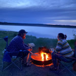Alyson and Jake of Team Cascadin on their camping adventure sitting around a fire in the evening